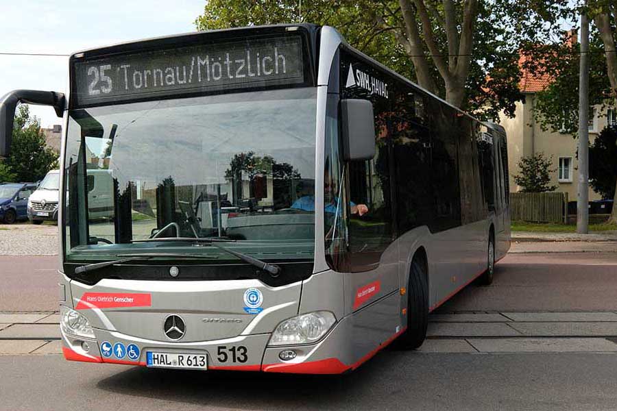 Moderner Mercedes-Stadtbus der Linie 25 mit Zielanzeige 'Tornau/Mötzlich' steht auf einer Straße vor Bäumen und Häusern.