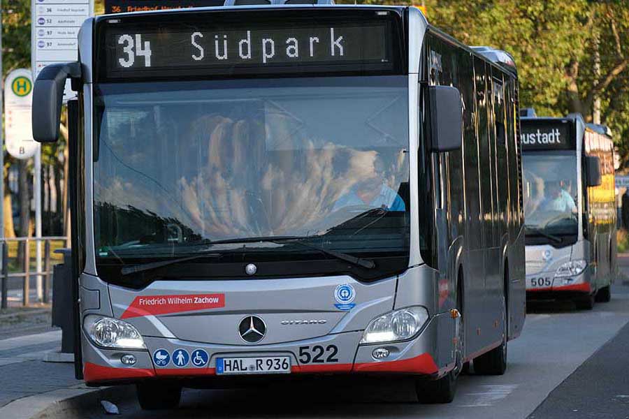 Buslinie 34 mit Zielanzeige 'Südpark' steht an einer Haltestelle, dahinter ein weiterer Bus.