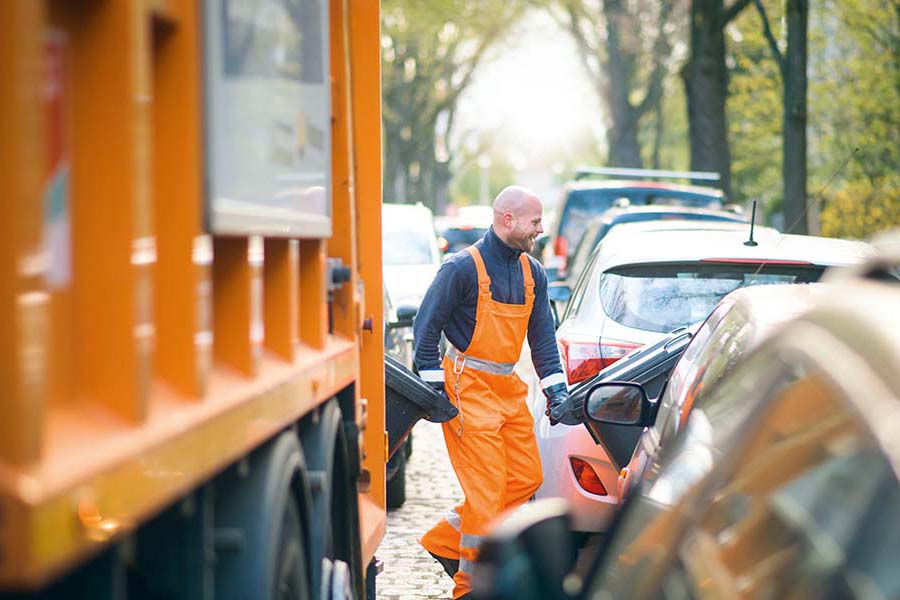 Mitarbeiter rangiert zwei Mülltonnen.