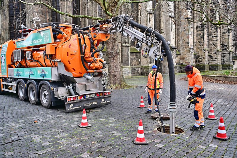 Hochdruck-Spülfahrzeug im Einsatz, zwei Mitarbeiter spülen einen Kanal.