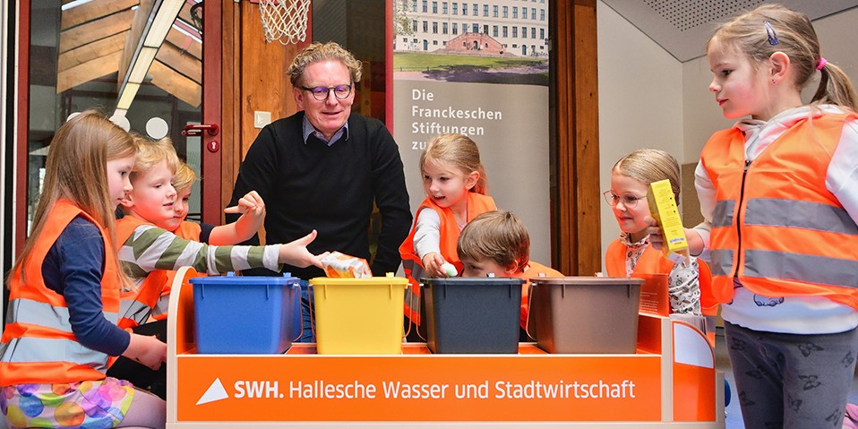Peter Günther, Geschäftsführer der HWS und Kinder einer Kita spielen das neue Mülltrennspiel