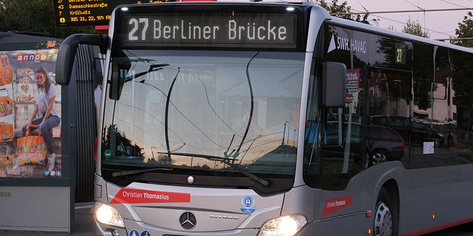 Die Buslinie mit der Zielanzeige '27 Berliner Brücke' steht bei Dämmerung an einer Haltestelle.