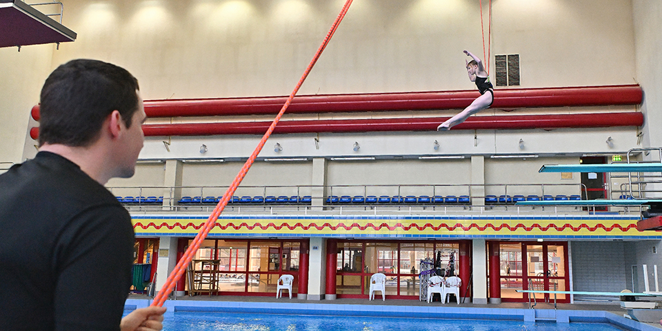 Trainer Normen Becker unterstützt Springerin mit der Longe beim Sprung ins Wasser.