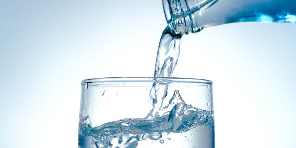 Wasser wird in Trinkglas eingeschenkt.