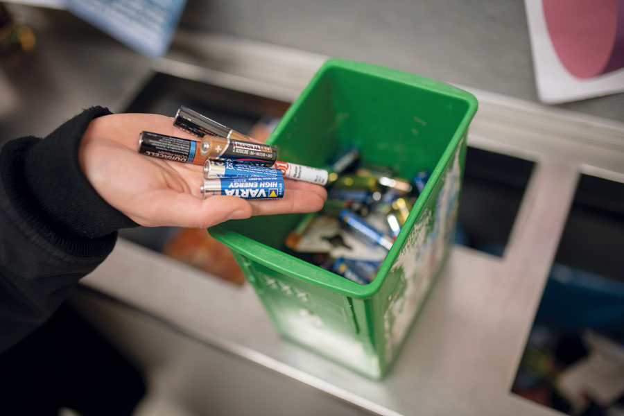 Batterien werden in eine grüne Box zur fachgerechten Entsorgung gelegt.