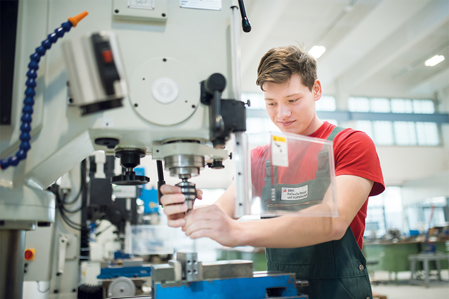 Ein Auszubildender in der Lernwerkstatt arbeitet an einer Maschine