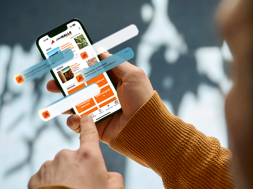 Eine Nahaufnahme eines Smartphones, welches die App Mein HALLE Zuhause zeigt.