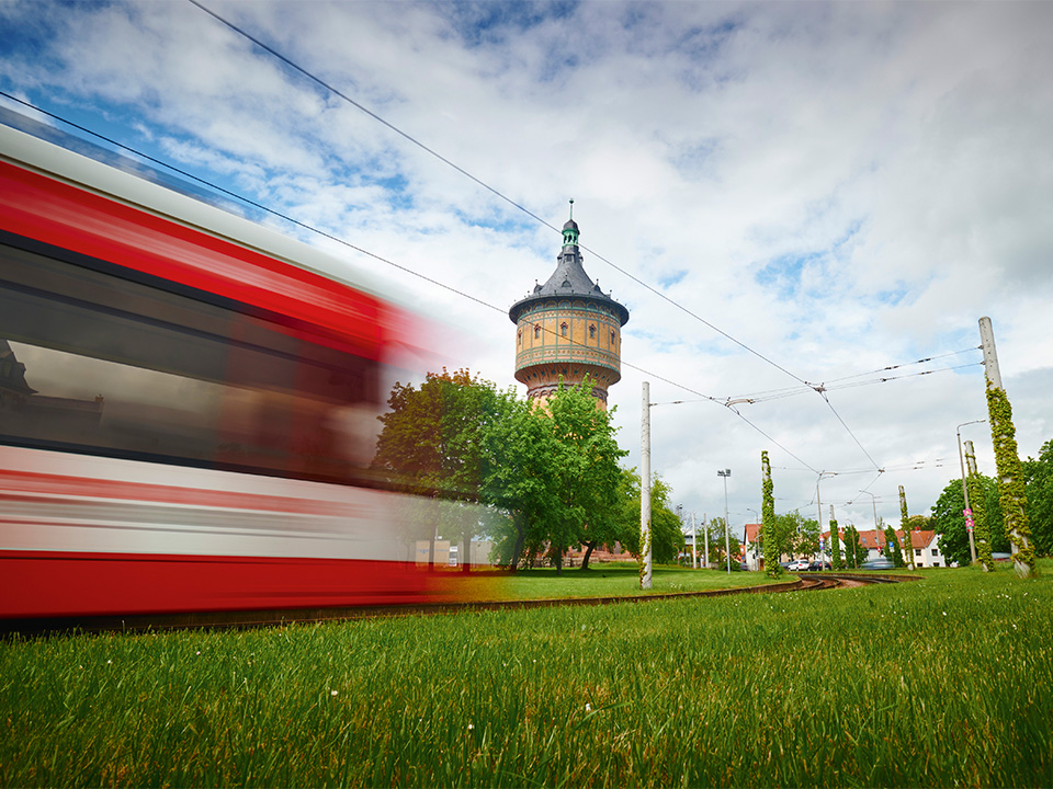 Bahn neben begrünter Fläche. Im Hintergrund der Wasserturm Nord.