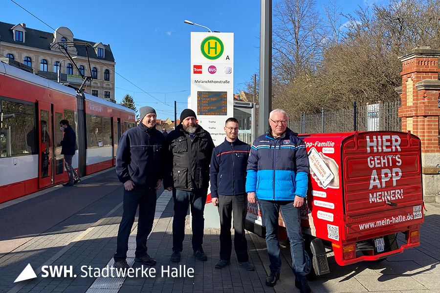 Vier Herren stehen vor der neuen Fahrgastinformationsstele.