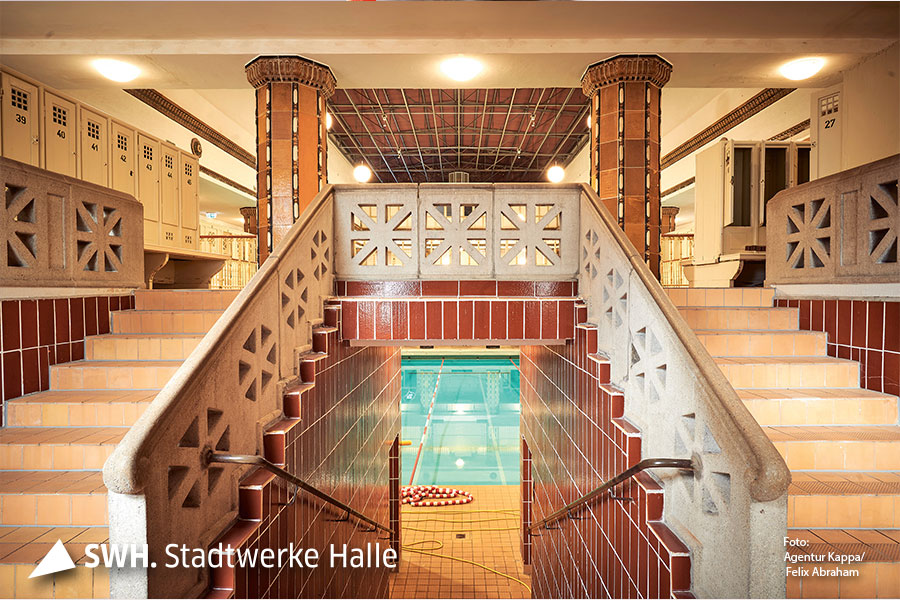 Ein Blick in das historische Stadtbad Halle wo sich rechts und links ein Treppenaufgang befindet und in der Mitte das Wasserbecken.