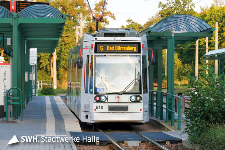 Das Bild zeigt eine weiße Straßenbahn an einer Haltestelle. Als Ziel steht "5 - Bad Dürrenberg".