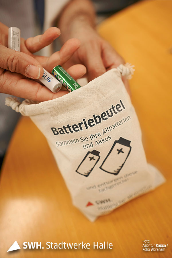 Eine Hand wirft Batterien in einen Batteriebeutel