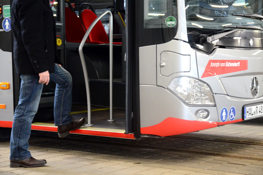 Eine Nahaufnahe wie ein dunkel gekleideter Mann in einen silbernen Bus der HAVAG steigt.