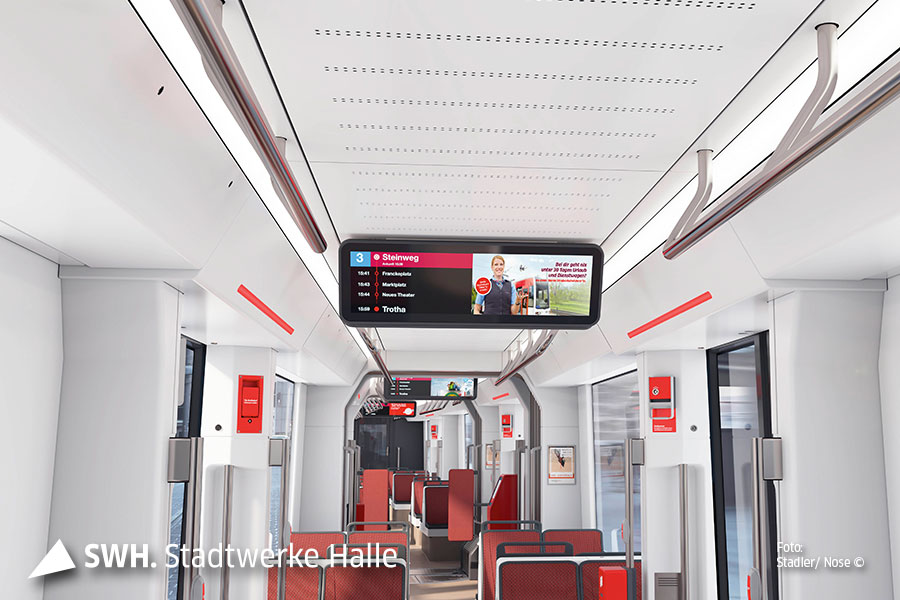 Ein Blick in eine leere Straßenbahn mit roten Sitzen von Innen. Oberhalb ein Monitor an der Decke mit Fahrgastinformationen.