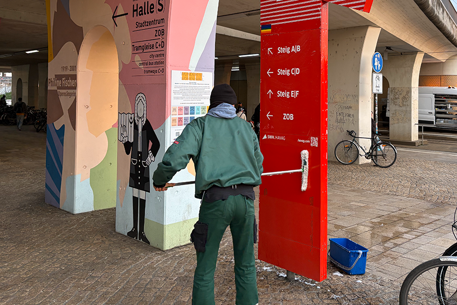Mitarbeiter putzt am Hauptbahnhof eine Informationssäule