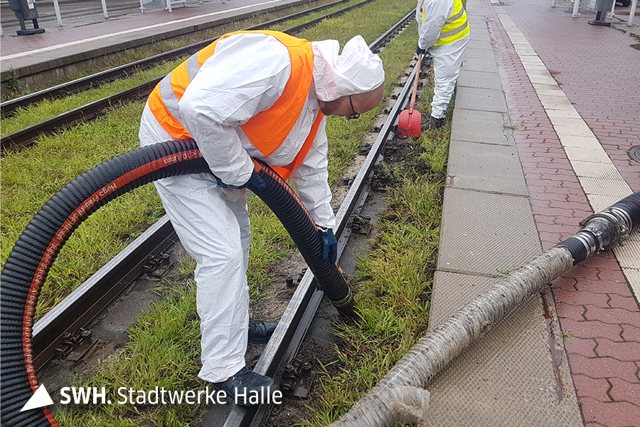 Ein Mann reinigt das Gleisbett einer Straßenbahn-Gleisanlage