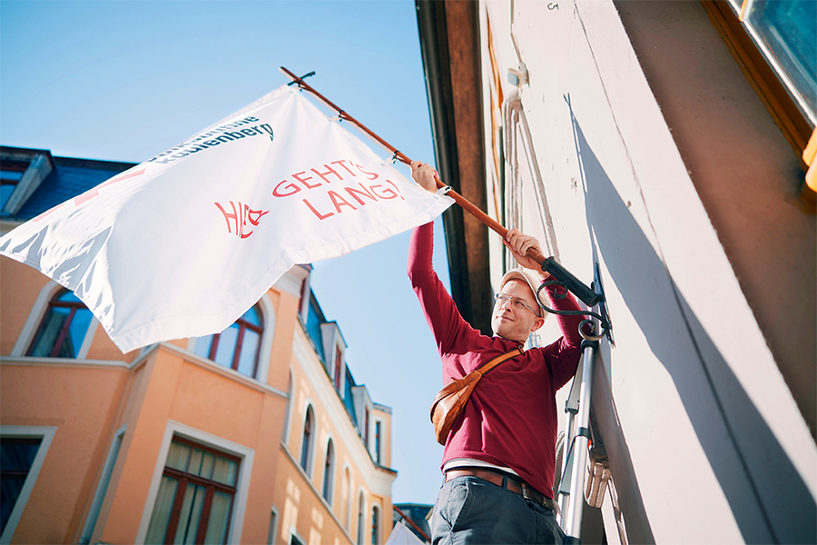 Jonas Schütte hängt Fahne an der Theaterwand auf.