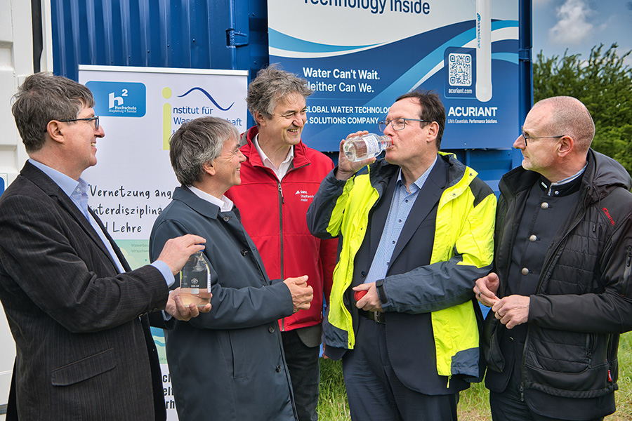 Ein Gruppe von eingeladenen Offiziellen zum Fördermittelbescheid vor einem Container.