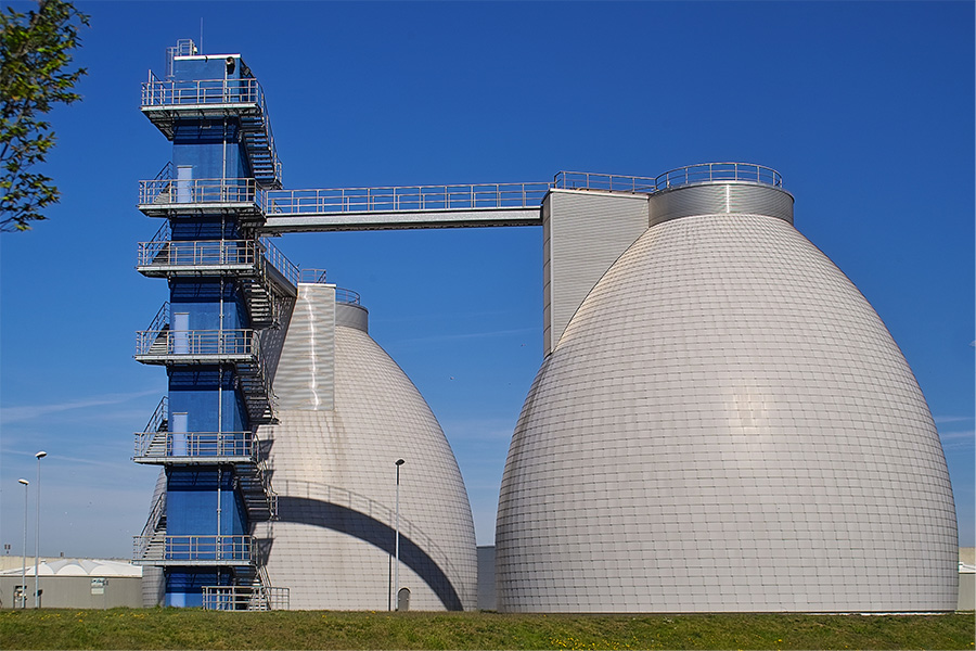 Strahlend blauer Himmel im Hintergrund. Mittig im Bild sind die beiden grauen Faultürme der HWS zu sehen. Davor eine große blaue Treppe, um auf die Türme zu gelangen. 