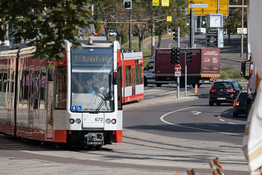 Eine rote Straßenbahn der HAVAG fährt eine leichte Kurve. Rechts ist die Straße mit wenigen Autos. Links die Straßenbahn.