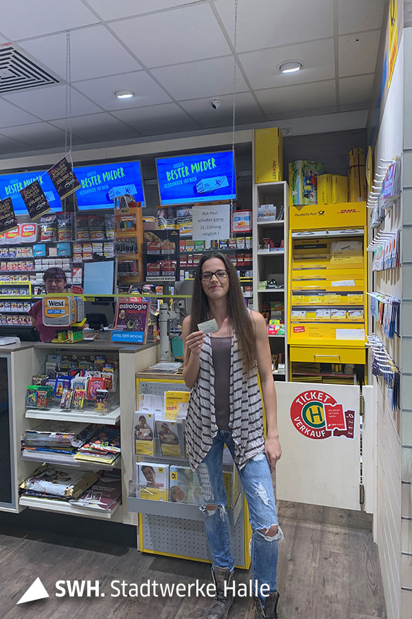 Eine Frau steht im Geschäft eines Lotto-Zeitschriften-Tabakwaren in Halle und hält ein HAVAG-Ticket direkt in die Kamera.