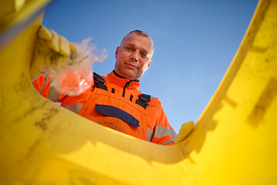 HWS Mitarbeiter Martin Kügler schaut in eine gelbe Tonne
