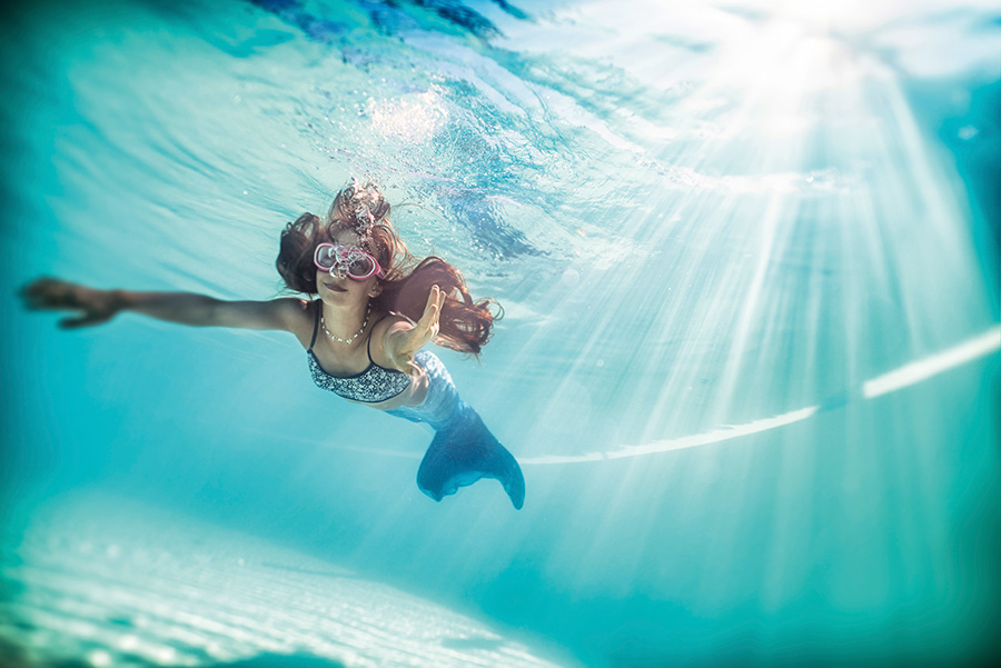 Das Foto zeigt ein Mädchen, das unter Wasser mit einer Meerjungfrauflosse schwimmt.