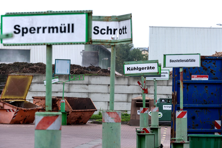 Schilder mit Aufschriften, was wo zu entsorgen ist stehen hintereinander auf dem Wertstoffmarkt.