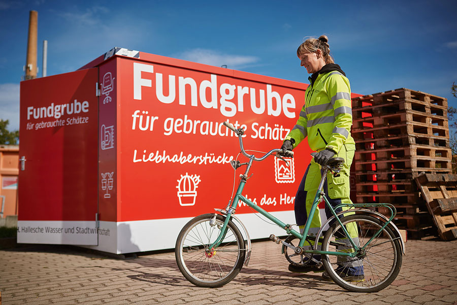 Eine HWS Mitarbeiterin präsentiert ein Fahrrad welches vor dem Müll gerettet wurde.