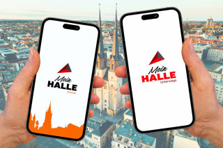 Vor dem Hintergrund der Stadt Halle werden zwei Handys gehalten. Auf dem einen läuft die App "Mein HALLE Zuhause" auf dem anderen "Mein HALLE Unterwegs"