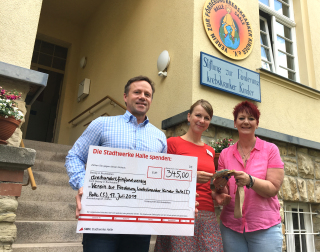 Drei Menschen bei der Spendenübergabe an den Verein zur Förderung krebskranker Kinder in Halle (Saale).  