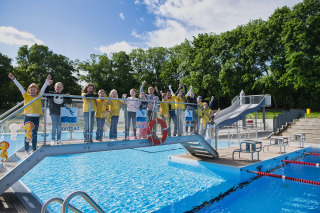 Kinder stehen freudig auf einer kleinen Brücke des Freibads Nordbad Halle.