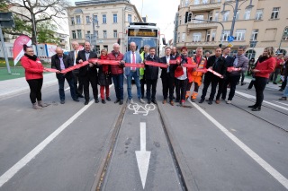 Das Foto zeigt alle Beteiligten des Bauvorhabens. Jeder hält ein Stück des Bandes nach dem Durchschnitt in der Hand und schaut in die Kamera. Sie stehen in der Großen Steinstraße vor einer Straßenbahn. 