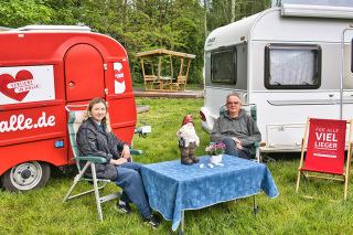 Campingplatzbesucher sitzen vor zwei Wohnwagen auf dem Campingplatz am Nordbad