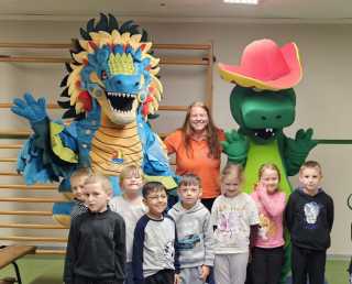 Autorin steht mit den Maskottchen und Kindern vor der Kamera.