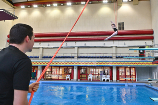 Trainer Normen Becker unterstützt Springerin mit der Longe beim Sprung ins Wasser.