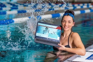 Eine junge Frau präsentiert im Wasserbecken der Robert-Koch.-Schwimmhalle auf einem Notebook die neue Webseite der Bäder Halle GmbH.