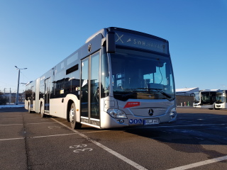 Foto des neuen Busses auf einem Parkplatz. Der Bus ist silberfarben. Als Zielaufschrift steht ein großes X und dann SWH.HAVAG. Das Kennzeichen lautet HAL-R-682. Es ist ein Gelenkbus. Der Himmel ist blau und wolkenlos, die Sonne scheint.