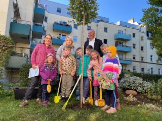 Die Kinder, Erzieherinnen und EVH-Geschäftsführer Olaf Schneider stehen an dem neuen Baum.
